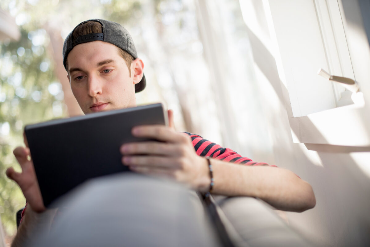 Mann um die 30 hält ein IPad in der Hand und schaut rein.